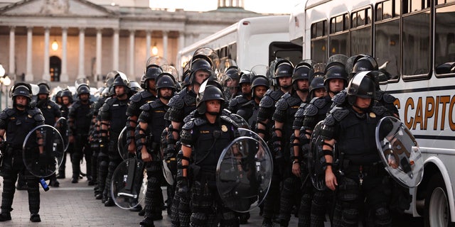 Capitol police stand dressed in riot gear as protestors gather near the Supreme Court in response to the ruling on Roe v. 韦德.