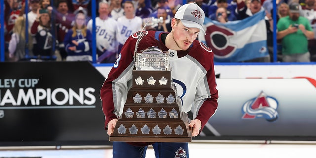 Cale Makar #8 of the Colorado Avalanche accepts the Conn Smythe trophy for Stanley Cup playoff MVP from NHL Deputy Commissioner Bill Daly after Game Six of the 2022 Stanley Cup Final at Amalie Arena on June 26, 2022 in Tampa, Florida. The Avalanche defeated the Lightning four games to two.
