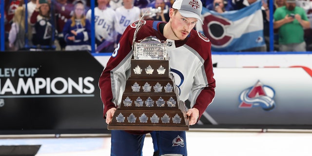 Cale Makar #8 of the Colorado Avalanche accepts the Conn Smythe trophy for Stanley Cup playoff MVP from NHL Deputy Commissioner Bill Daly after Game Six of the 2022 Stanley Cup Final at Amalie Arena on June 26, 2022 in Tampa, Florida. The Avalanche defeated the Lightning four games to two.