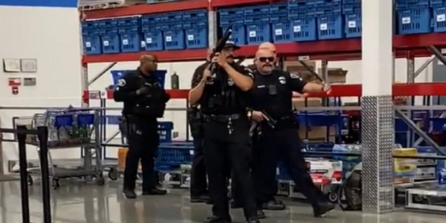 Police are seen drawing their weapons while responding to the Sam's Club in Fullerton, California.