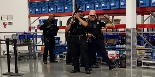 Police are seen drawing their weapons while responding to the Sam's Club in Fullerton, California.