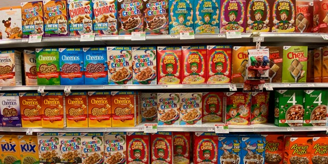 Family-sized General Mills and Quaker Cereal cereal products are shown in a grocery store.