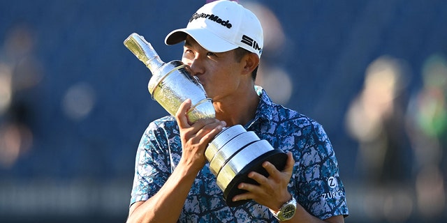 US golfer Collin Morikawa kisses the trophy as he poses for pictures with the Claret Jug, the trophy for the Champion Golfer of the Year, after winning the 149th British Open Golf Championship at Royal St George's, Sandwich in south-east England on July 18, 2021.