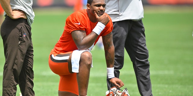 Cleveland Browns quarterback Deshaun Watson kneels on the field during an NFL football practice at the team's training facility Wednesday, June 8, 2022, in Berea, Ohio.