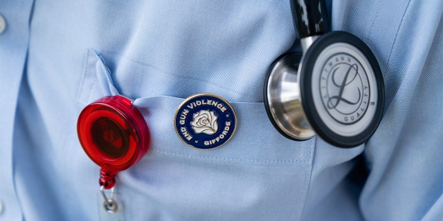 A medical student and member of Scrubs Addressing the Firearm Epidemic wears a End Gun Violence pin during a news conference at the Gun Violence Memorial on the National Mall in Washington, D.C., Tuesday, June 7, 2022. 