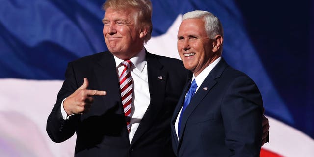 Donald Trump and Mike Pence pose together on a stage. 