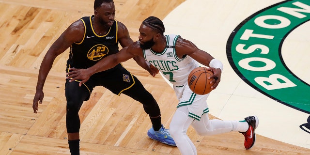 Celtics guard Jaylen Brown drives against Golden State Warriors forward Draymond Green Wednesday, June 8, 2022, in Boston.