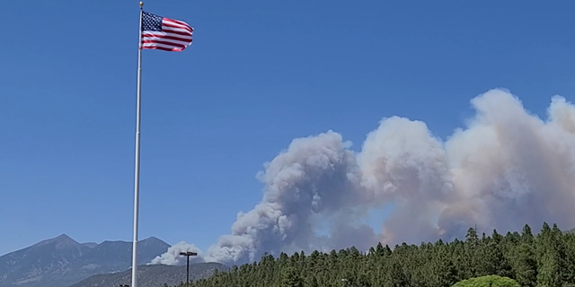 Foto de la bandera estadounidense ondeando sobre un incendio forestal en Arizona