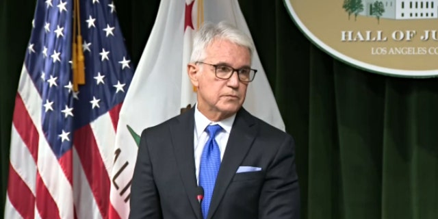 Los Angeles District Attorney George Gascon frowns during a news briefing.