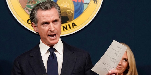 FILE: California Gov. Gavin Newsom displays a bill he signed that shields abortion providers and volunteers in California from civil judgements from out-of-state courts during a news conference in Sacramento, Calif., June 24, 2022.