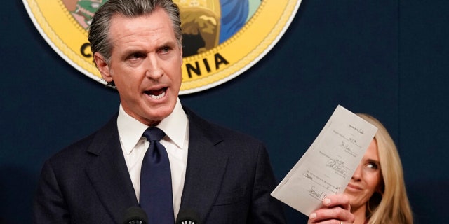 FILE: California Gov. Gavin Newsom displays a bill he signed that shields abortion providers and volunteers in California from civil judgements from out-of-state courts during a news conference in Sacramento, Calif., June 24, 2022.