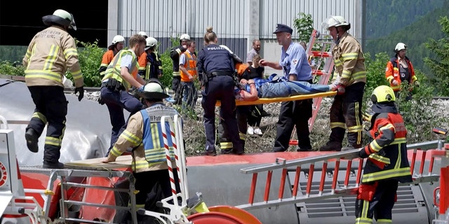 This video grab shows policemen and firemen rescuing a person from a derailed train on June 3, 2022 in Burgrain near Garmisch-Partenkirchen, southern Germany.
