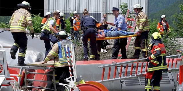This video grab shows policemen and firemen rescuing a person from a derailed train on June 3, 2022 in Burgrain near Garmisch-Partenkirchen, southern Germany.