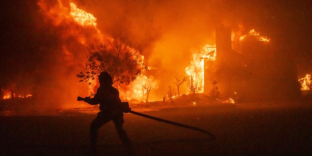 Bloomberg Best of the Year 2020: A firefighter carries a hose as buildings burn in the Skyhawk Park neighborhood of East Santa Rosa during wildfires in Sonoma County, California, U.S., on Sunday, Sept. 27, 2020. 