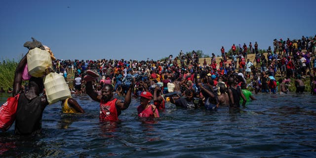 TOPSHOT - Haitian migrants, part of a group of over 10,000 people staying in an encampment on the US side of the border, cross the Rio Grande river to get food and water in Mexico,  after another crossing point was closed near the Acuna Del Rio International Bridge in Del Rio, Texas on September 19, 2021. (Photo by PAUL RATJE / AFP) (Photo by PAUL RATJE/AFP via Getty Images)