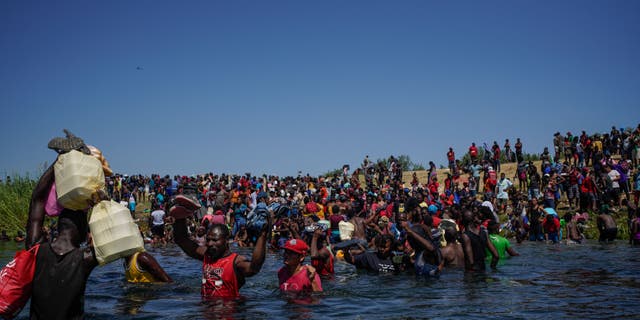 TOPSHOT - Haitian migrants, part of a group of over 10,000 people staying in an encampment on the US side of the border, cross the Rio Grande river to get food and water in Mexico,  after another crossing point was closed near the Acuna Del Rio International Bridge in Del Rio, Texas on September 19, 2021. (Photo by PAUL RATJE / AFP) (Photo by PAUL RATJE/AFP via Getty Images)