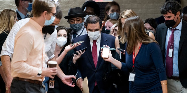 Reporters surround Rep. Henry Cuellar as he leaves a House Democrats caucus meeting in the basement of the Capitol.