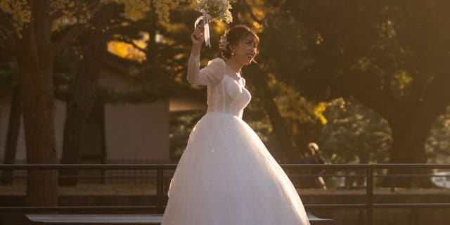 A woman prepares for a wedding photo shoot under ginkgo trees in autumn colours outside Tokyo station on November 25, 2021. (Photo by Philip FONG / AFP) (Photo by PHILIP FONG/AFP via Getty Images)