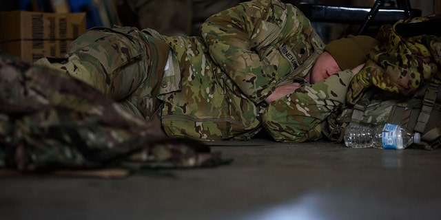 A soldier with the 82nd Airborne division naps while waiting to deploy to Poland on Feb. 14, 2022 at Fort Bragg, Fayetteville, North Carolina. 