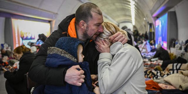 Sergyi Badylevych (L), 41, hugs his wife Natalia Badylevych (R), 42, and baby in an underground metro station used as bomb shelter in Kyiv on March 2, 2022. 
