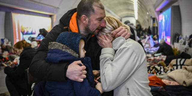 Sergyi Badylevych (L), 41, hugs his wife Natalia Badylevych (R), 42, and baby in an underground metro station used as bomb shelter in Kyiv on March 2, 2022.