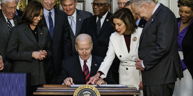 U.S. President Joe Biden, center, signs H.R. 2471, the "Consolidated Appropriations Act, 2022," in the Indian Treaty Room of the White House in Washington, D.C., U.S., on Tuesday, March 15, 2022.