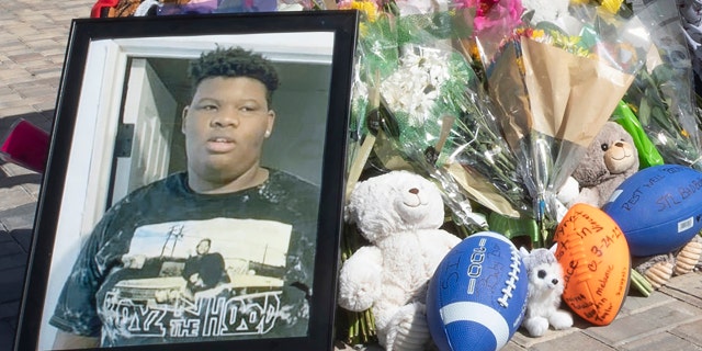 Visitors stand next to a memorial while a family member lights candles for Tyre Sampson, 14, who was killed when he fell from the Orlando Free Fall ride at ICON Park in Orlando, Florida, on March 26, 2022. 