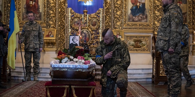 A man touches the coffin as he pays respects to journalist Maks Levin during his funeral on April 4, 2022 in Kyiv, Ukraine. 