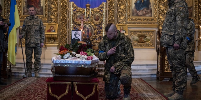 A man touches the coffin as he pays respects to journalist Maks Levin during his funeral on April 4, 2022 in Kyiv, Ukraine.