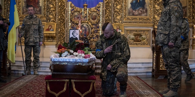 A man touches the coffin as he pays respects to journalist Maks Levin during his funeral on April 4, 2022 in Kyiv, Ukraine. 