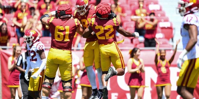 USC Trojans, à esquerda, Joe Bryson, Kyle Ford e Darwin Barlow comemoram o pouso do avião em 23 de abril de 2022, no Los Angeles Memorial Coliseum. 