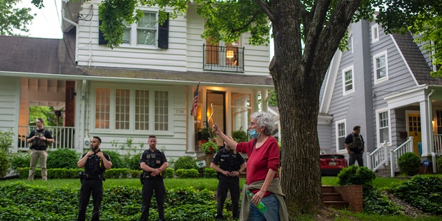 An abortion-rights advocate holds a clothes hanger while passing the home of U.S. Supreme Court Justice Brett Kavanaugh on May 18, 2022. 