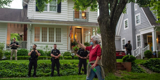 A pro-choice advocate holds a clothes hanger while passing the home of Supreme Court Justice Brett Kavanaugh on May 18, 2022.
