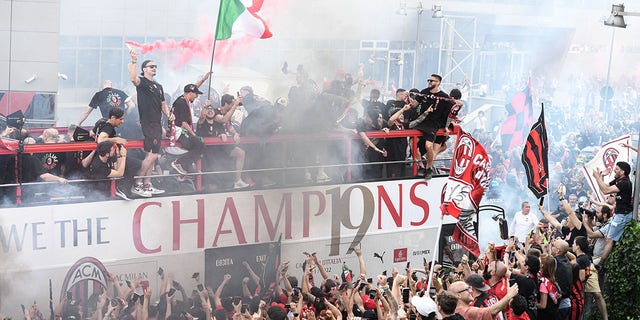 AC Milan players parade with the Scudetto Trophy on a double-decker bus in front of the club's headquarters Casa Milan in Milan, on May 23, 2022.
