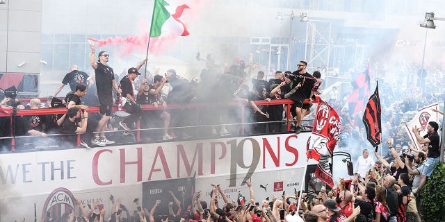 AC Milan players parade with the Scudetto Trophy on a double-decker bus in front of the club's headquarters Casa Milan in Milan, on May 23, 2022.