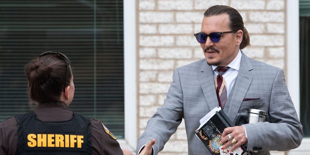 Johnny Depp shakes hands with a deputy as he departs from the civil trial against Amber Heard at Fairfax County Circuit Court on May 26, 2022.
