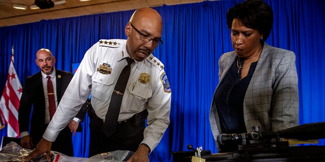 City officials including Mayor Muriel Bowser, right, Police Chief Robert J. Contee III, center and Deputy Mayor for Public Safety Chris Geldart, left, with the guns collected from the shooter who terrorized the Van Ness area after discussing the rising violence at a press conference, in Washington, DC.