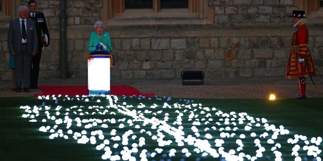 Queen Elizabeth touches the Commonwealth Nations Globe to start the lighting of the Principal Beacon outside of Buckingham Palace.