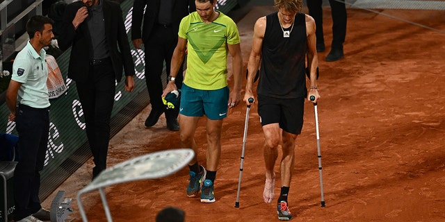 Germany's Alexander Zverev (R) walks with crutches next to Spain's Rafael Nadal on court after being injured during his men's semi-final singles match on day thirteen of the Roland-Garros Open tennis tournament at the Court Philippe-Chatrier in Paris on June 3, 2022. 