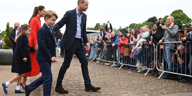 El duque y la duquesa de Cambridge y sus hijos hablan con los simpatizantes durante una visita al castillo de Cardiff en Gales.