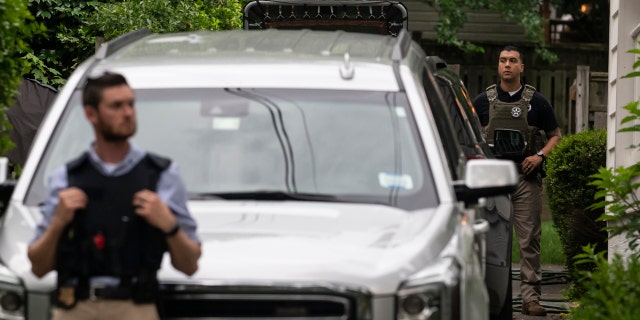 Law enforcement officers stand guard as protesters march past Supreme Court Justice Brett Kavanaugh's home.