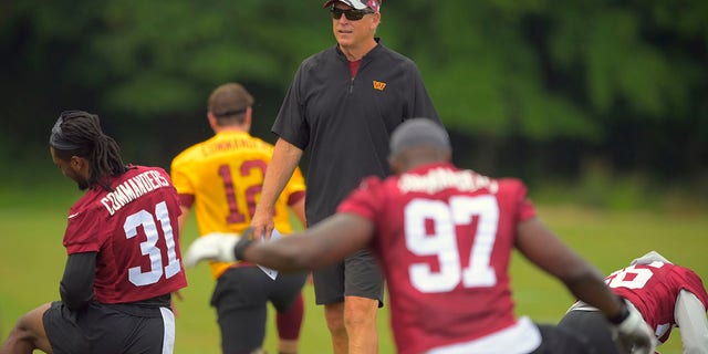 Washington Commanders defensive coordinator Jack Del Rio walks among his defenders as they warm up during an OTA for Washington Commanders at their training center in Ashburn, Va., June 8, 2022. 
