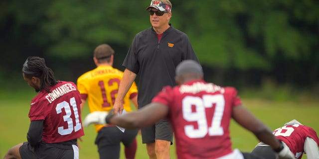 Jack Del Rio, Defender Coordinator of the Washington Commanders, walks between defenders on June 8, 2022, during a warm-up during practice at a training facility in Ashburn, Virginia.