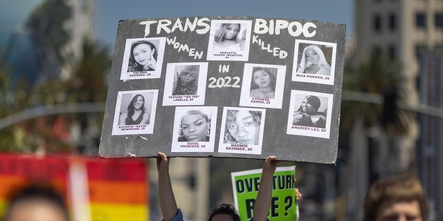 A participant holds photos of transgender people killed in 2022 at the annual Pride Parade on June 12, 2022, in the Hollywood section of Los Angeles.