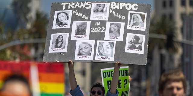 A participant holds photos of transgender people killed in 2022 at the annual Pride Parade on June 12, 2022, in the Hollywood section of Los Angeles.