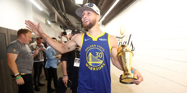 Stephen Curry #30 of the Golden State Warriors looks on and smiles with the Bill Russell NBA Finals MVP Award after Game Six of the 2022 NBA Finals on June 16, 2022, at TD Garden in Boston. 