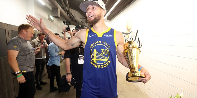 Stephen Curry #30 of the Golden State Warriors looks on and smiles with the Bill Russell NBA Finals MVP Award after Game Six of the 2022 NBA Finals on June 16, 2022, at TD Garden in Boston. 