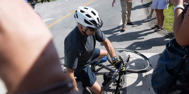 US President Joe Biden falls off his bicycle as he approaches well-wishers following a bike ride at Gordon's Pond State Park in Rehoboth Beach, Delaware, on June 18, 2022. - Biden took a tumble as he was riding his bicycle Saturday morning, but was unhurt.