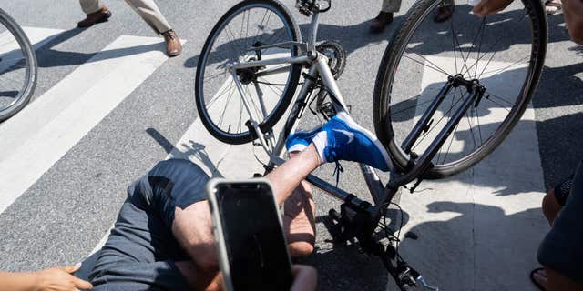 US President Joe Biden falls off his bicycle as he approaches well-wishers following a bike ride at Gordon's Pond State Park in Rehoboth Beach, Delaware, en Junio 18, 2022.