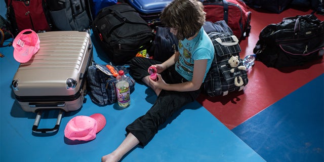 KYIV, UKRAINE - JUNE 20: A girl plays with a toy next to her and other childrens belongings on June 20, 2022 near Kyiv, Ukraine. The goal of the 7fields camp, which is near Zalissia National Nature Park, is to support the children of families displaced from other parts of Ukraine since the February 24 invasion, but who are remaining in the country. Over the summer, the camp aims to support 300 children between the ages of 7 and 15, with activities like swimming pools, tennis, soccer, yoga, chess and craft-making, in addition to therapy sessions. (Photo by Alexey Furman/Getty Images)